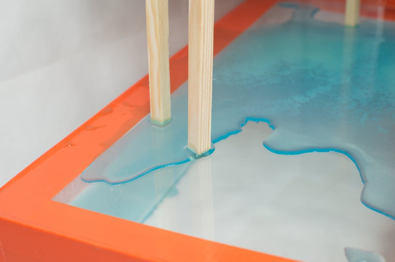 High angle of timber object placed above transparent glass with colored water as art installation